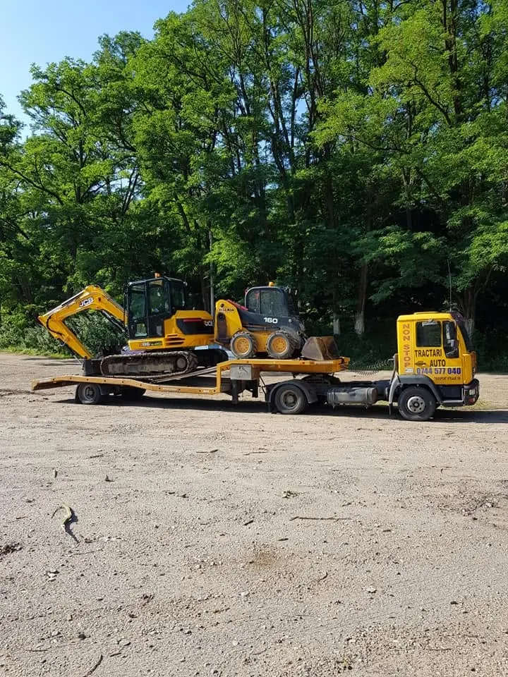 Excavator pe trailer, la marginea unui câmp