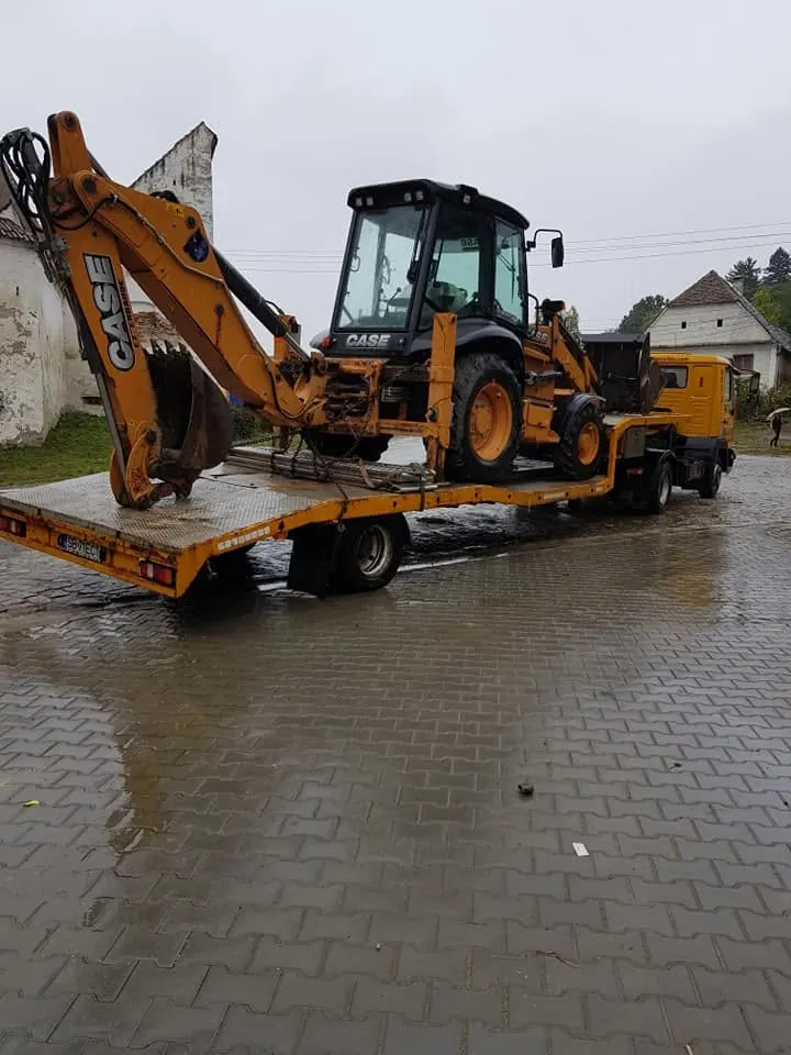 Buldoexcavator urcat pe trailer, pe o zi ploioasă